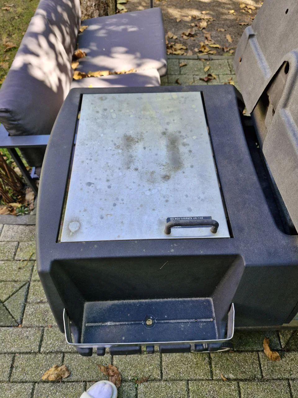Zamknięta metalowa pokrywa bocznego stanowiska i otwarta komora poniżej w grillu Broil King
