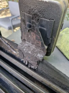 Skorodowany metalowy wspornik przy ciemnym module na obrzeżu grilla